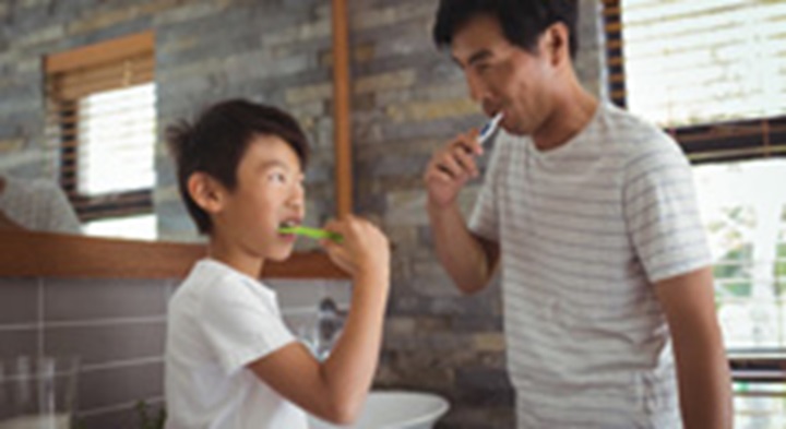 Father and son brushing teeth.