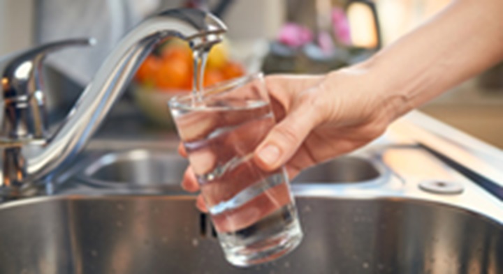 Person filling up glass of water from the tap.