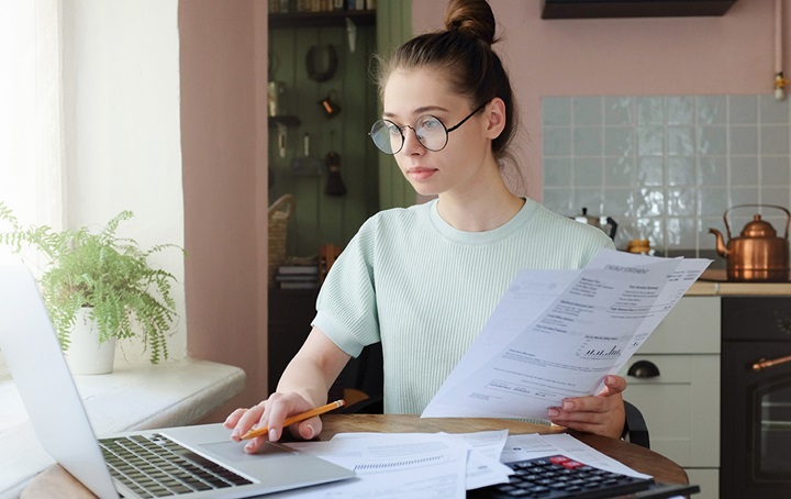 Woman reading a computer screen and paperwork simultaneously