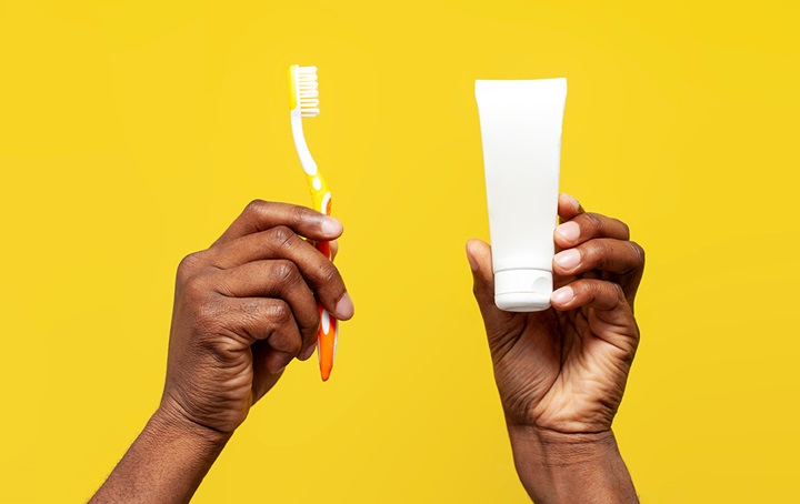 Person holding toothbrush and toothpaste up to the sky