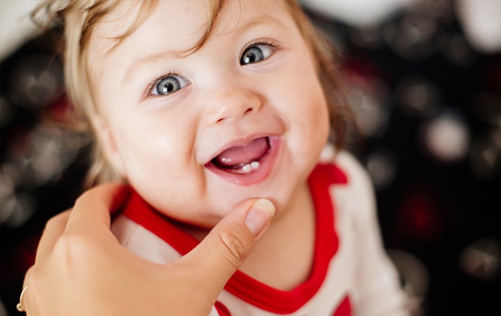 A young baby smiling, showing teeth.