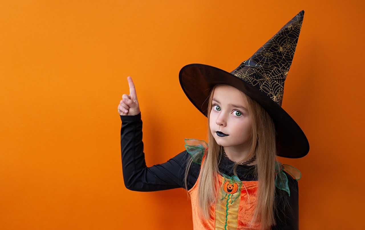 Girl dressed as witch pointing finger up