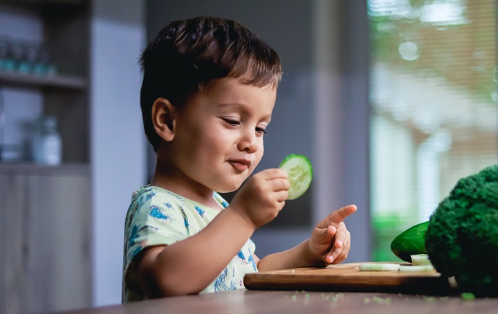 Toddler eating a cucumber slice