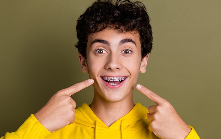 Boy smiling pointing at his braces
